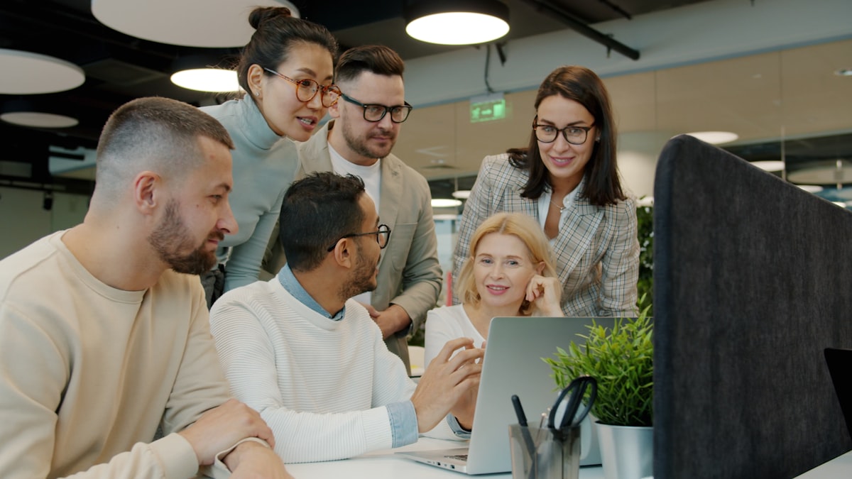 Equipo de trabajo reunido alrededor de una notebook en una oficina moderna